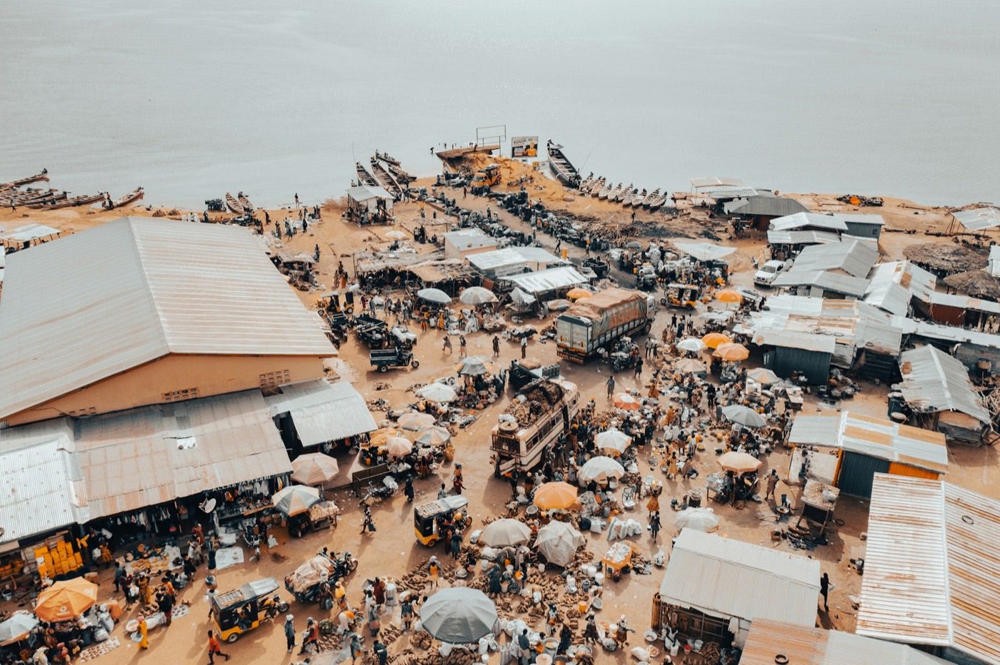 A busy outdoor market by the water, seen from above